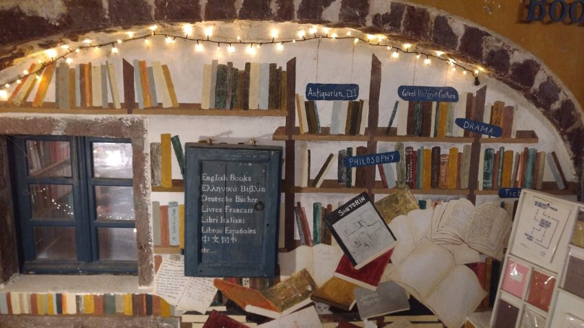 Entrance to Atlantis Bookstore in Santorini with arched doorway and painting of books on shelves